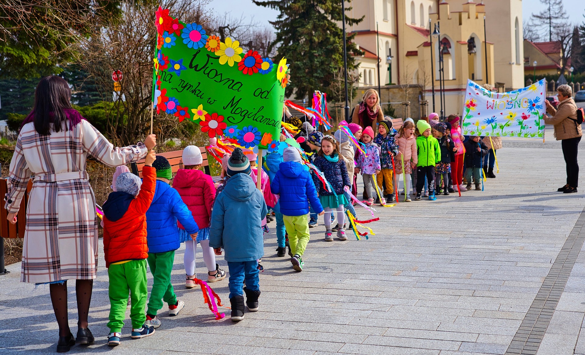dzieci i panie z przedszkola z transparentami na powitanie wiosny