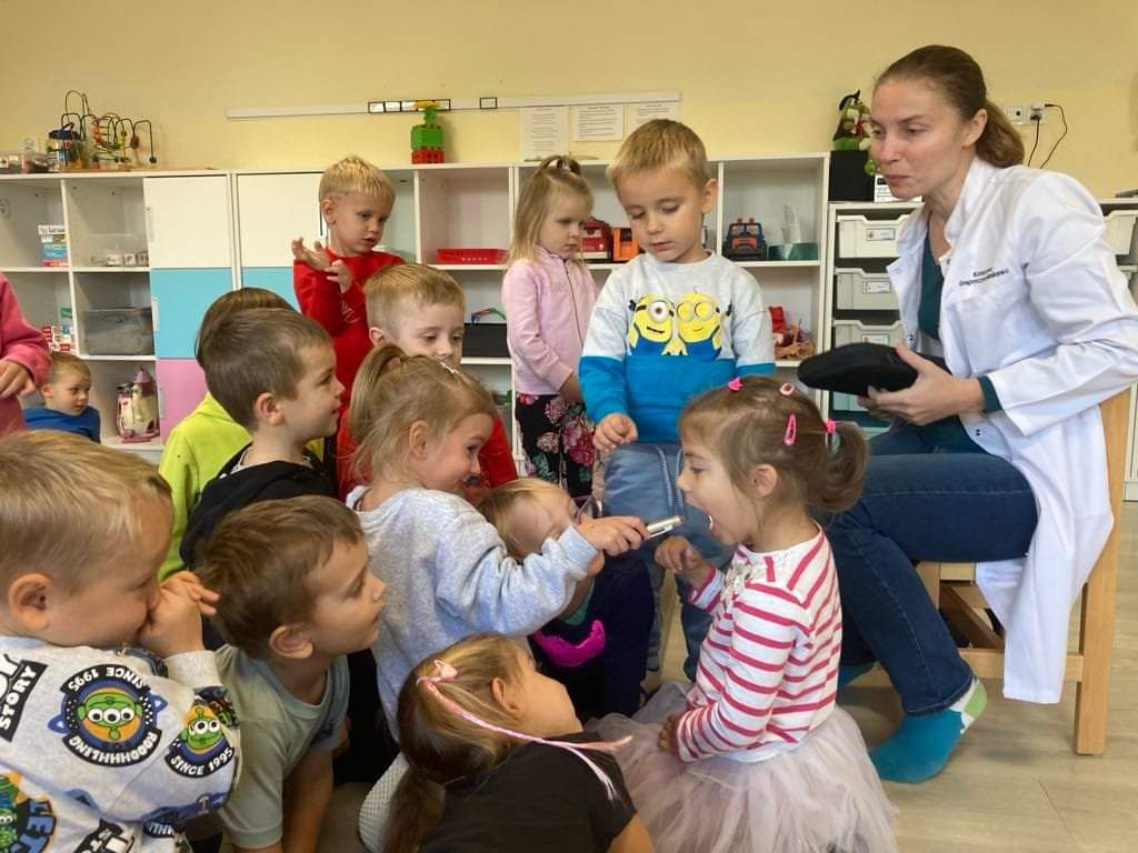 Dzieci ogladaja stetoskop i oglądają latarka gardła kolegi