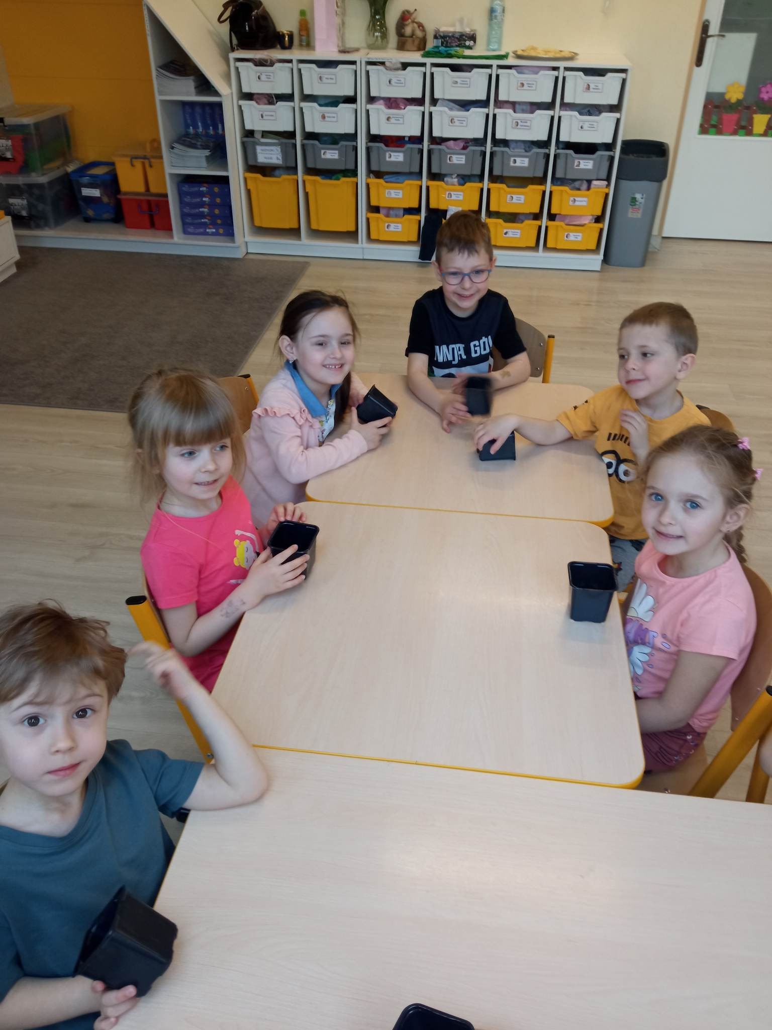 dzieci przy stolikach z doniczkami