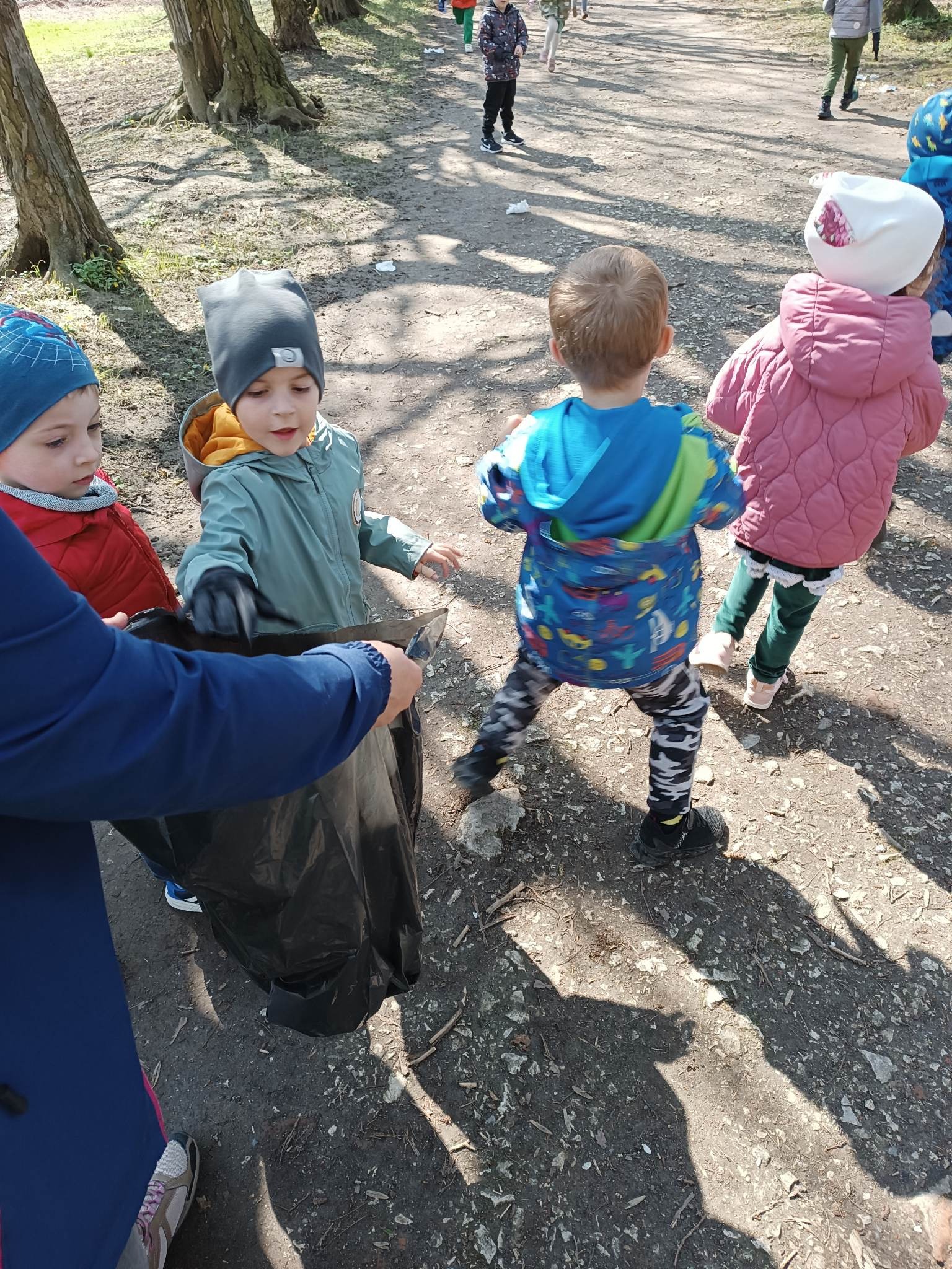 dzieci z Biedronek szukają w parku śmieci