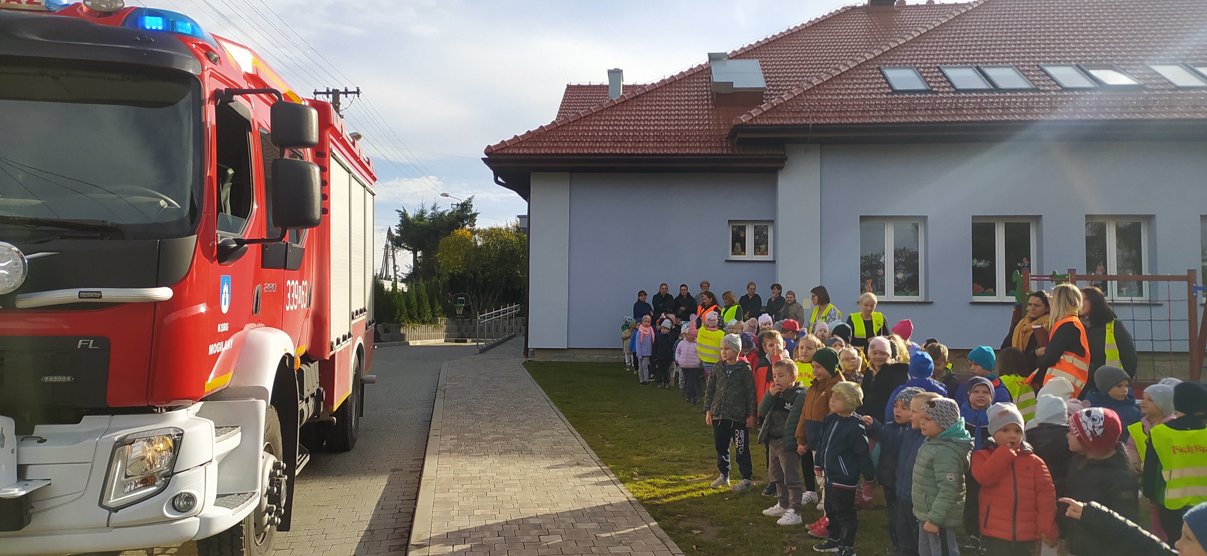 dzieci na tle przedszkola i samochód strażacki